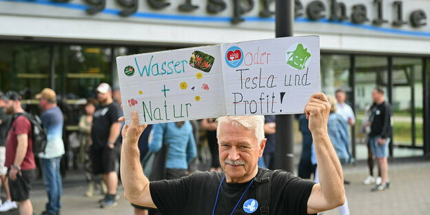 Ein Teilnehmer einer Bündnisinitiative protestiert vor der Müggelspreehalle in Hangelsberg während der Gemeinderatssitzung